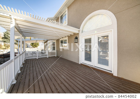 Exterior of a house with white handrails and wood plank flooring 84454002