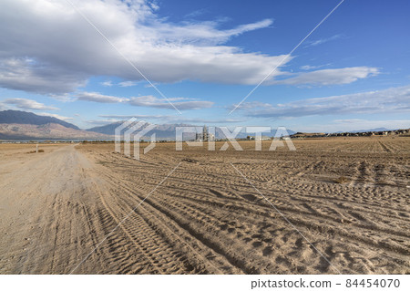 Tractor tracks on a farmland with a background of mountain range and lake in Saratoga Springs, Utah Tractor tracks on a farmland with a background of mountain range and lake in Saratoga Springs, Utah 84454070