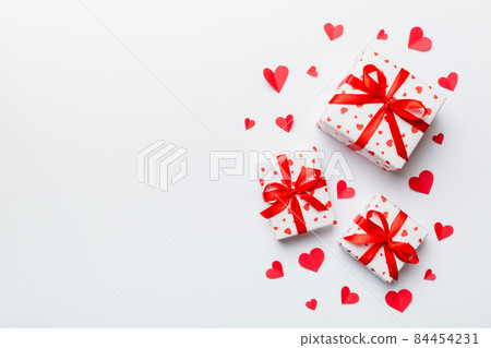 Valentine day composition: red gift box with bow and heart. Christmas present. View from above. Space for text. Holday greeting card Valentine day composition: red gift box with bow and heart. Christmas present. View from above. Space for text. Holday greeting card 84454231
