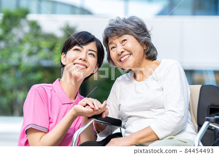 A senior woman in a wheelchair and a young helper shooting cooperation "LINK FOREST" 84454493