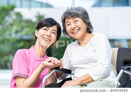 A senior woman in a wheelchair and a young helper shooting cooperation "LINK FOREST" 84454495