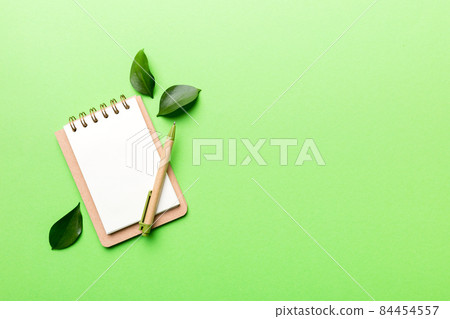 eco-friendly Empty notebook with pen and green leaf on Colored background for note 84454557