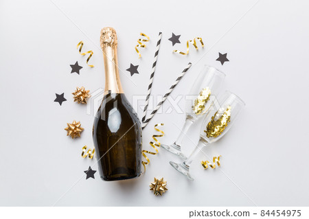bottle of champagne with glasses and colorful confetti on colored background. top view flay lay 84454975