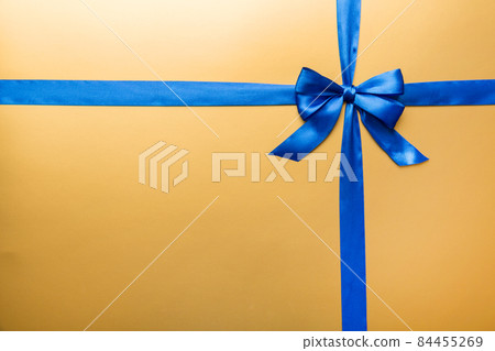 Top view of blue ribbon rolled and blue bow isolated on colored background. Flat lay with copy space 84455269