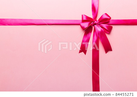 Top view of purple ribbon rolled and pink bow isolated on colored background. Flat lay with copy space 84455271