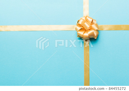 Top view of gold ribbon rolled and yellowbow isolated on colored background. Flat lay with copy space Top view of gold ribbon rolled and yellowbow isolated on colored background. Flat lay with copy space 84455272