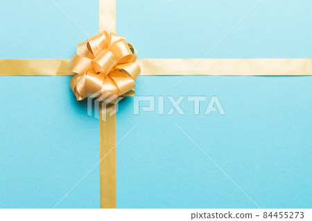 Top view of gold ribbon rolled and yellowbow isolated on colored background. Flat lay with copy space Top view of gold ribbon rolled and yellowbow isolated on colored background. Flat lay with copy space 84455273