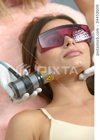 Non injection mesotherapy. Doctor and patient in clinic. Rejuvenation cosmetology tool. Woman aesthetic skin face procedure. 84458609