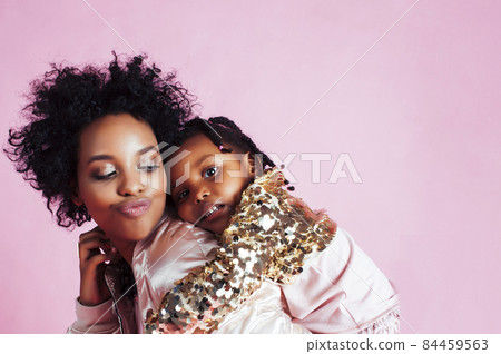 young pretty african-american mother with little cute daughter hugging, happy smiling on pink background, lifestyle modern people concept 84459563