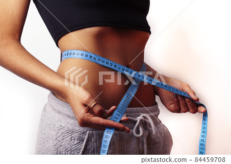 woman measuring waist with tape on knot, african tan isolated woman measuring waist with tape on knot, african tan isolated 84459708