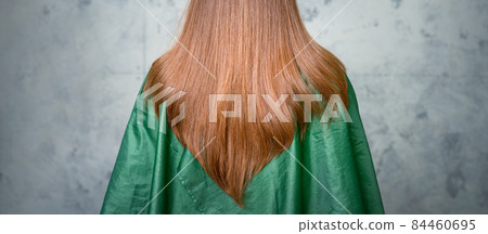 Rear View of a woman with long brown hair against a gray background. 84460695