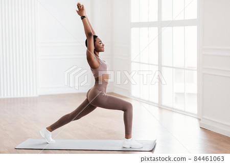 Young black woman standing in warrior pose on fitness mat 84461063