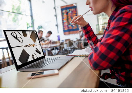 Cropped shot view of young woman working on laptop computer while sitting in modern cafe bar interior. Design. Web design Cropped shot view of young woman working on laptop computer while sitting in modern cafe bar interior. Design. Web design 84461233