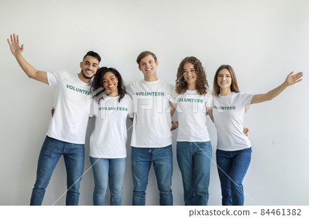 Group of positive millennial volunteers embracing and posing, being ready for work in charity organization Group of positive millennial volunteers embracing and posing, being ready for work in charity organization 84461382