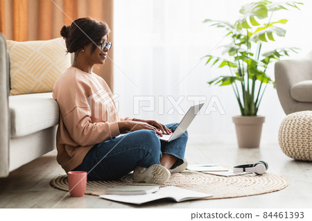 Side-View Of African American Female Using Laptop Computer At Home Side-View Of African American Female Using Laptop Computer At Home 84461393