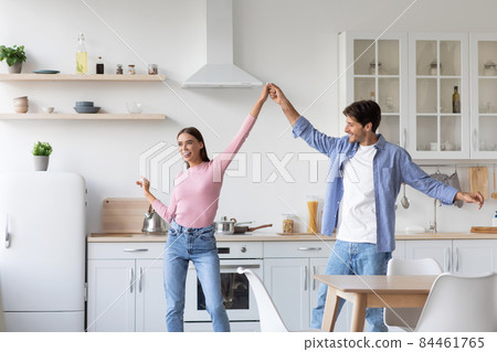Happy cheerful millennial husbands lady dancing, have fun together in kitchen interior 84461765
