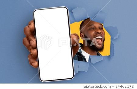 Black guy showing white empty smartphone screen through torn paper 84462178