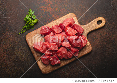 Beef raw meat cubes for stew on wooden cutting board Beef raw meat cubes for stew on wooden cutting board 84464737