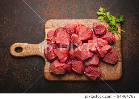 Beef raw meat cubes for stew on wooden cutting board Beef raw meat cubes for stew on wooden cutting board 84464762