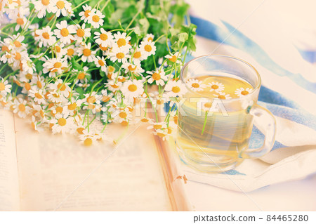 summer blurred background of camomile tea and old book tenderness spring sunbeams 84465280