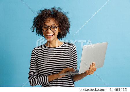 Cheerful young woman using laptop in studio 84465415