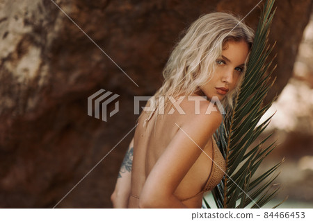 Sexy Beach Blonde Girl in Knitted Bikini With Palm Leaf Outdoors on Nature 84466453