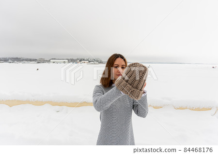 Portrait of young elegant brunette girl in dress on background winter road with warm hat Portrait of young elegant brunette girl in dress on background winter road with warm hat 84468176