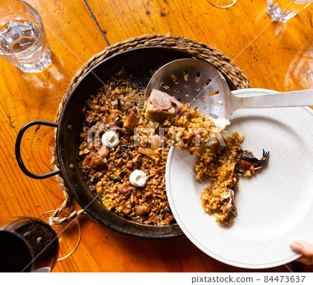 Customer putting paella from pan to plate Customer putting paella from pan to plate 84473637