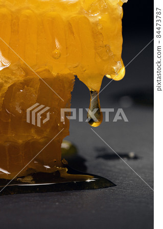 Drop of honey on honeycomb cut, close up. Honeycomb slice Drop of honey on honeycomb cut, close up. Honeycomb slice 84473787