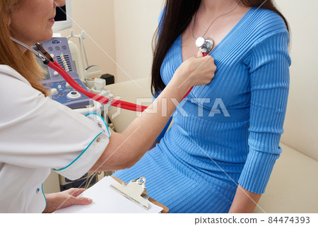 Doctor listening stethoscope with to heart of young female patient 84474393
