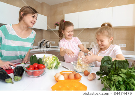 Mother and two daughters cooking in the kitchen and having fun, happy family and single mother concept Mother and two daughters cooking in the kitchen and having fun, happy family and single mother concept 84474479