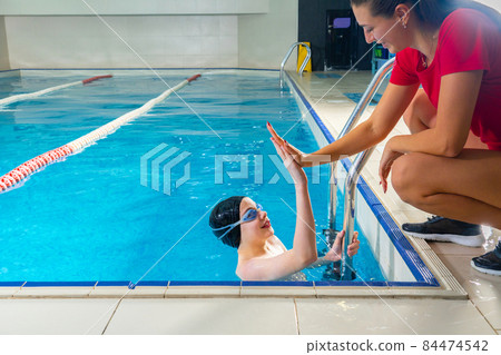 Female Coach In Water Giving preteen boy swimming Lesson In Indoor Pool Female Coach In Water Giving preteen boy swimming Lesson In Indoor Pool 84474542