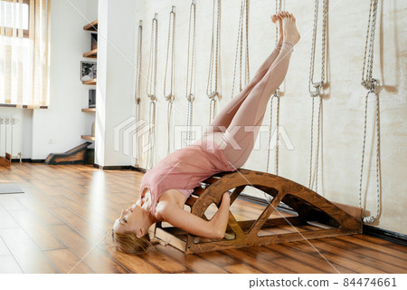 Mature woman doing Stretching Exercises On Yoga Backbend Bench in studio 84474661