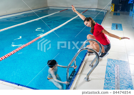 Female Coach In Water Giving preteen boy swimming Lesson In Indoor Pool 84474854