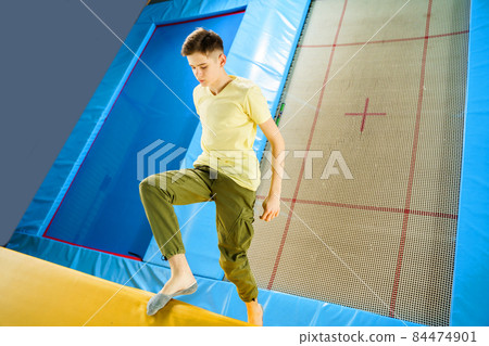 Teenage boy jumping on trampoline park in sport center Teenage boy jumping on trampoline park in sport center 84474901