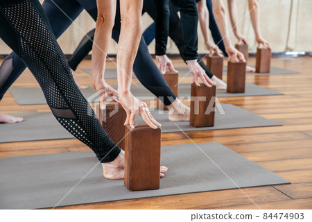 Group of four women practicing yoga standing in a row and stretching in yoga studio. Health concept 84474903