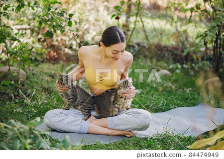 Girl sitting in a summer park with cute cat Girl sitting in a summer park with cute cat 84474949