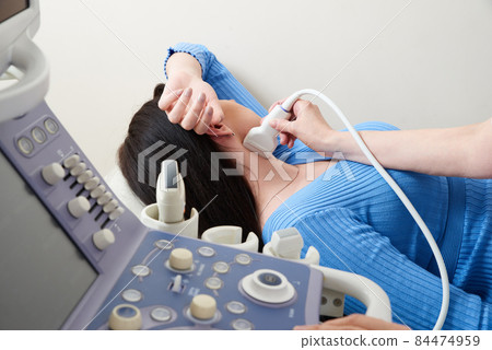 Doctor using ultrasound scanning machine examining female neck 84474959