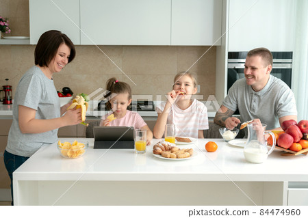 Smiling Family Dining Together at kitchen table and having fun, parents with two daughters 84474960