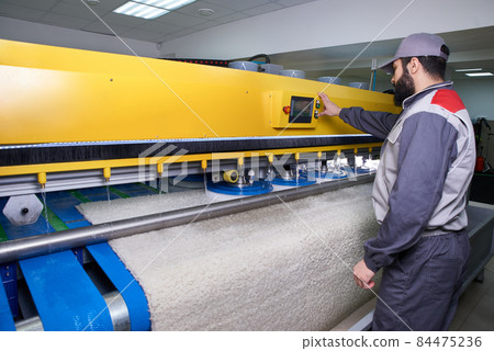 Laundry worker in the process of working on automatic machine for carpet washing in dry cleaning 84475236