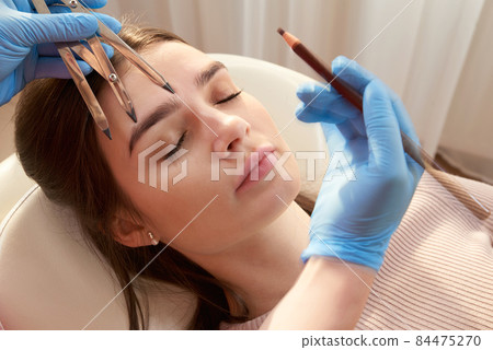 Cosmetologist measures the proportions of the eyebrows with the ruler. 84475270