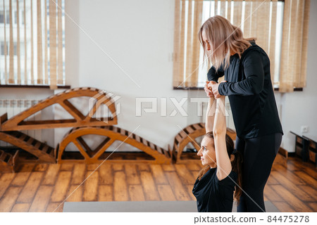 Yoga teacher is helping young woman to make poses at gym 84475278