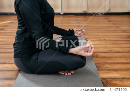 Cropped image of young lady make yoga exercises sitting in lotus asana Cropped image of young lady make yoga exercises sitting in lotus asana 84475293