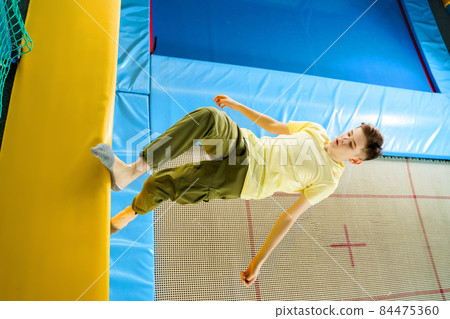 Teenage boy jumping on trampoline park in sport center Teenage boy jumping on trampoline park in sport center 84475360