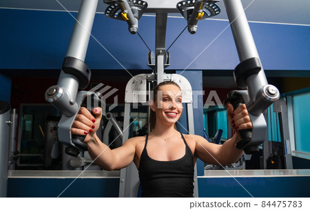 young fitness woman execute exercise with machine in gym 84475783