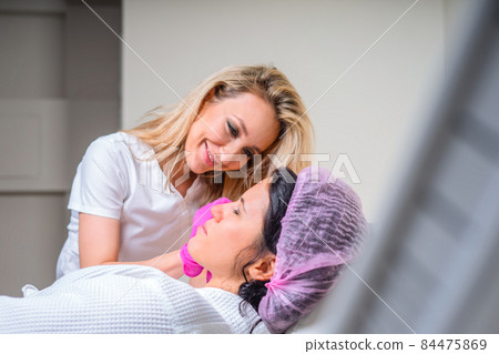 Cosmetologist using facial marker on patient face before beauty treatment in spa salon Cosmetologist using facial marker on patient face before beauty treatment in spa salon 84475869