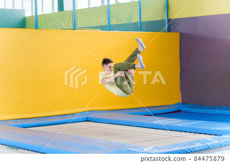 Teenage boy jumping on trampoline park in sport center  84475879