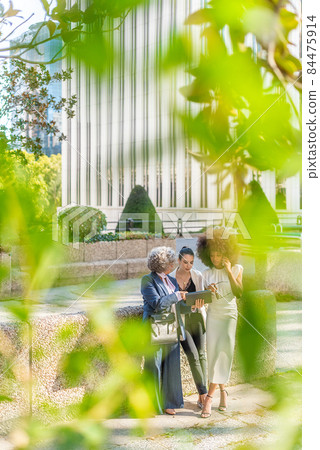 three businesswomen in the background looking at a tablet three businesswomen in the background looking at a tablet 84475914