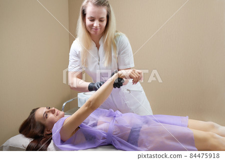 Waxing in beauty salon by professional. Beauty salon worker applying wax and tape to remove hair from arms 84475918