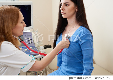 Doctor listening stethoscope with to heart of young female patient Doctor listening stethoscope with to heart of young female patient 84475969
